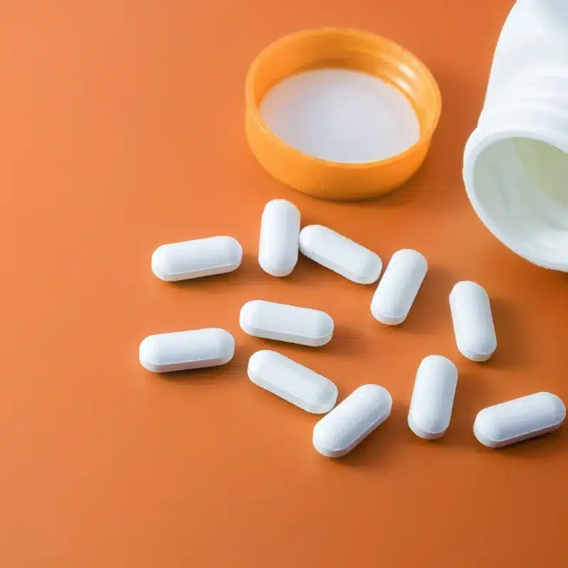 Is Methocarbamol Addictive? A bottle of white pills spilling onto an orange surface.