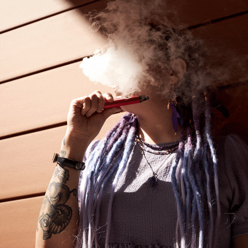 How Old Do You Have to Be to Vape: A person holding a vape pen in a cloud of smoke