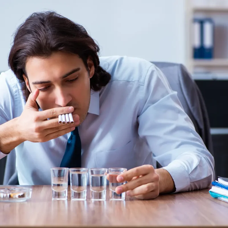 Gateway drugs. Man smoking cigars and holding glass of brandy.